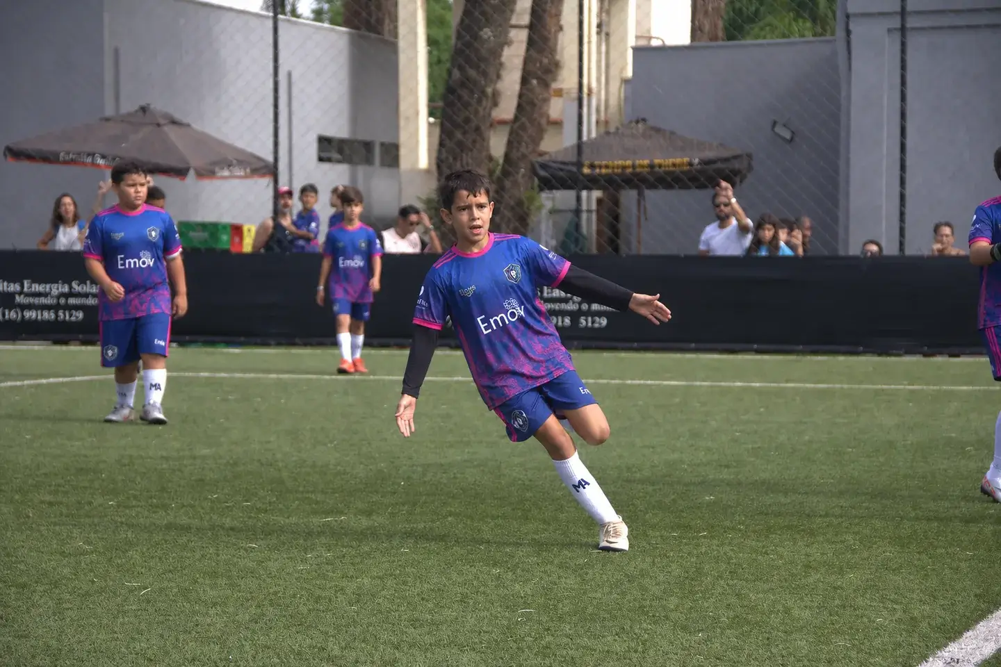 Crianças de uniforme jogando futebol em um campo